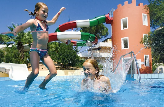 Kinder spielen in einem Pool, im Hintergrund ist eine Wasserrutsche zu sehen
