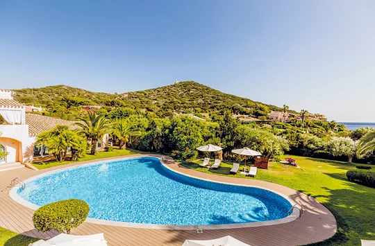 Blauschimmernder Pool inmitten grüner Natur beim Hotel Cala Caterina auf Sardinien