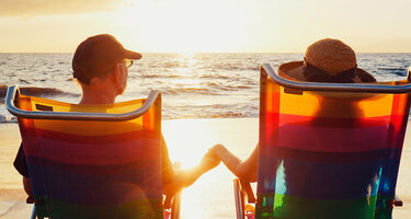 Ein Paar am Strand in Liegestühlen die den Sonnenuntergang anschauen