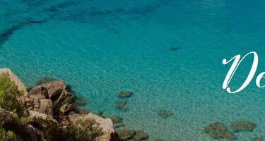 Viele Segelboote sind im Wasser. Im Hintergrund ist ein Felsen. Rechts ist der Schriftzug 