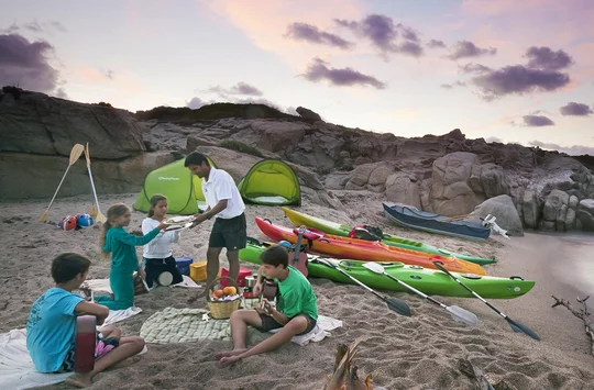 Kinder am Strand mit Lagerfeuer und Kajaks