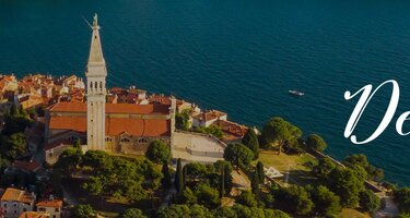 Eine Luftaufnahme der Insel Rovinj in Kroatien. Auf der Insel sind viele kleine Häuser und in der Mitte eine Kirche. Rechts ist der Schriftzug 