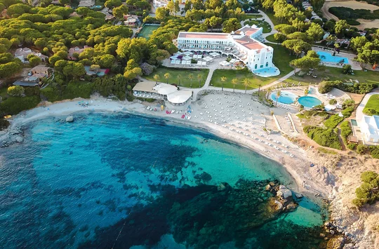 Luftansicht des Hotels Falkensteiner Capo Boi, vorne das blaue Meer und eine hell schimmernde Sandbucht